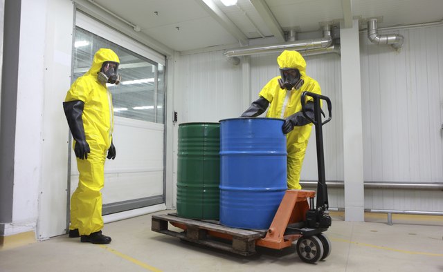 Two specialists dealing with barrels of chemicals