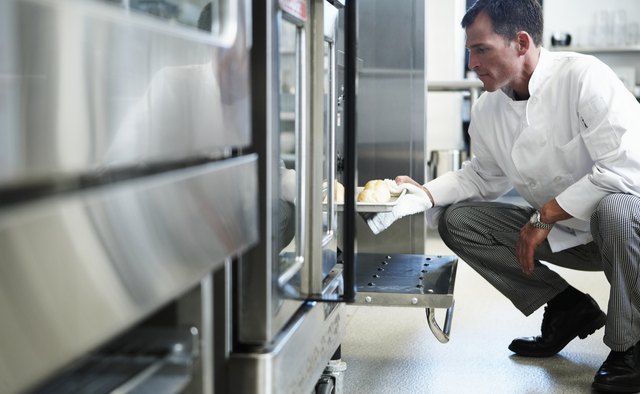 Chef taking food from oven in restaurant kitchen
