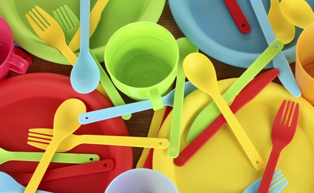 bright plastic disposable tableware on wooden background close-up