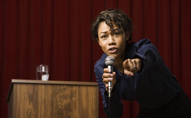 Mixed race businesswoman speaking on stage and pointing
