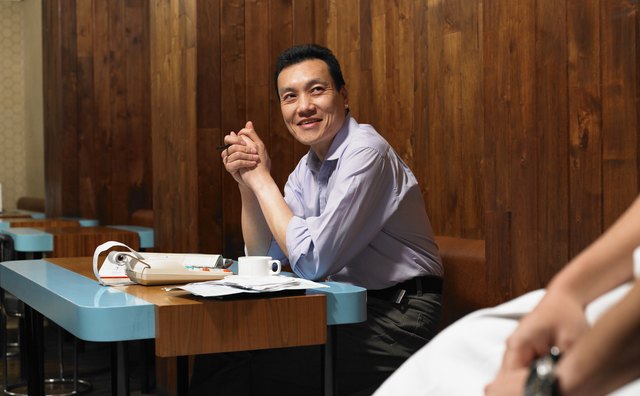 Man in restaurant by adlister, smiling at chef