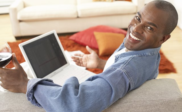 Mature man on sofa with laptop, smiling, portrait