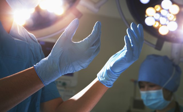 Midsection view of hands in surgical gloves and lights