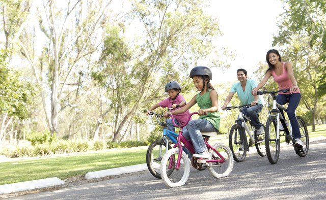 Young Family Riding Bikes In Park
