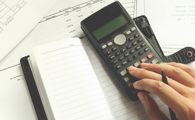 Cropped Hand Of Man Using Calculator On Desk At Office
