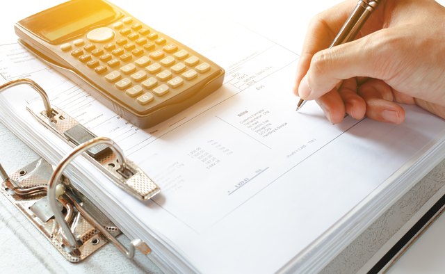 Cropped Hand Of Person Writing On Document On Table