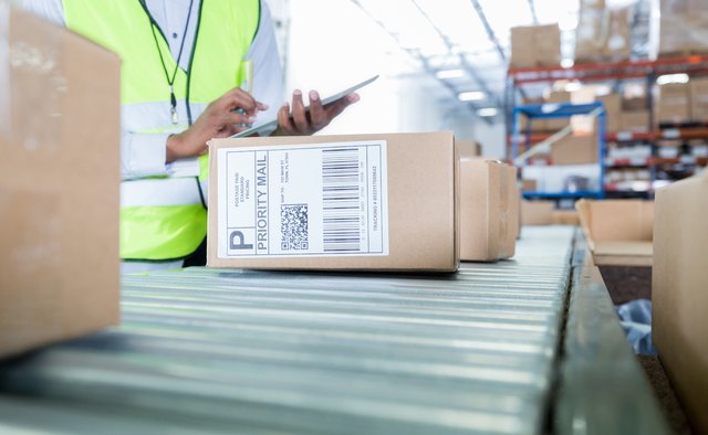 Unrecognizable male warehouse employee prepares package for mailing