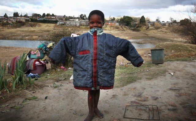 A young orphan holding up a donated coat.