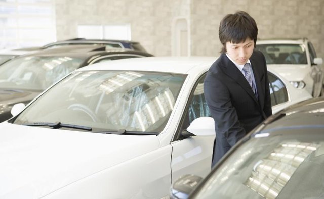 A car salesman inspecting one of his cars