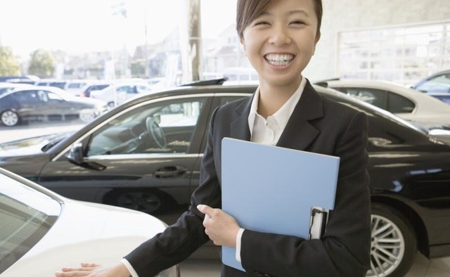 A female sales representative standing the show room of her dealership