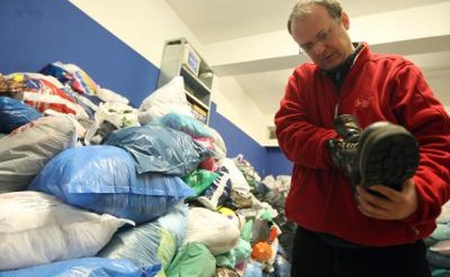 A volunteer checking the condition of a shoe in a homeless shelter.