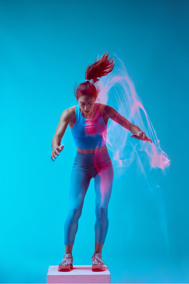 A sportswoman doing box jumps and exercising. Long exposure capture movement.