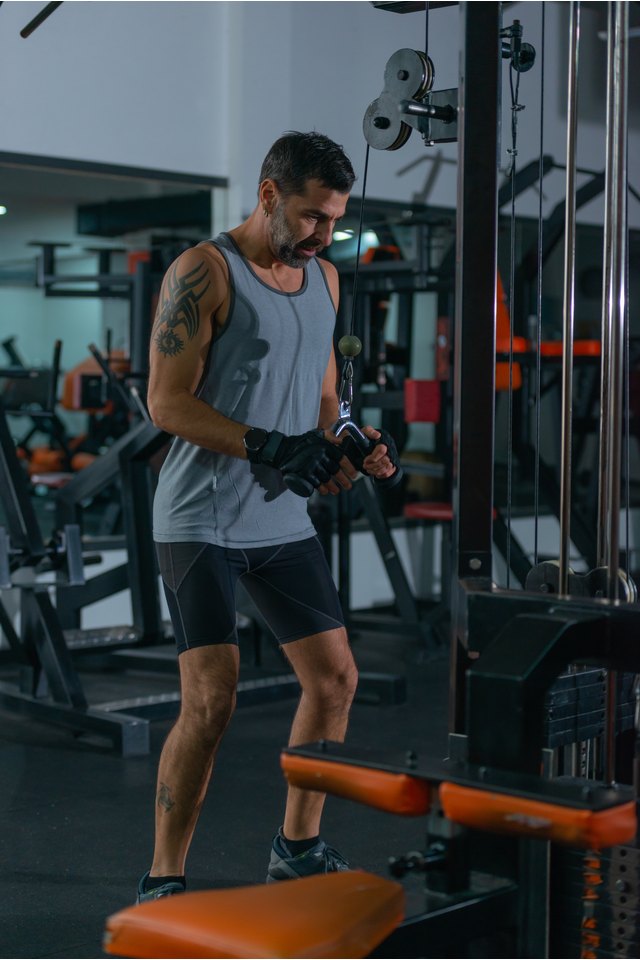 Bodybuilder doing cable triceps pushdowns during his workout in the gym