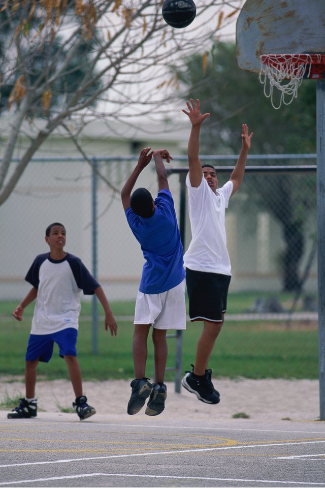 Three boys playing basketball outside