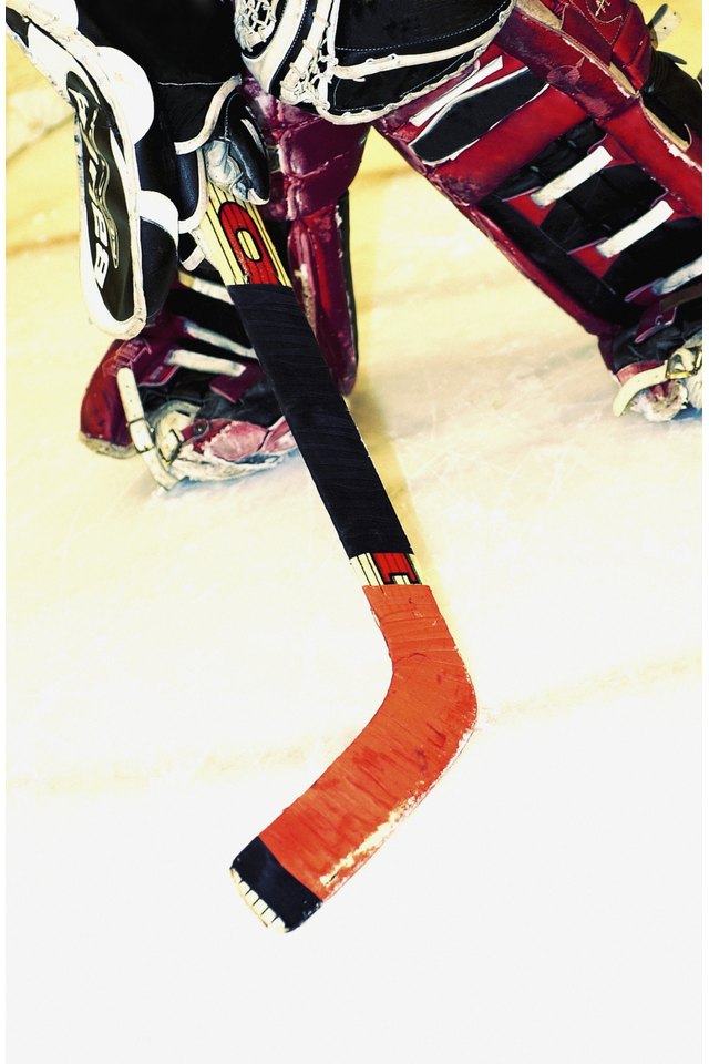 Legs of ice hockey player with hockey stick, close-up, part of