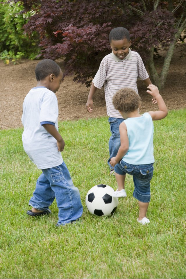 Two boys playing soccer with their sister