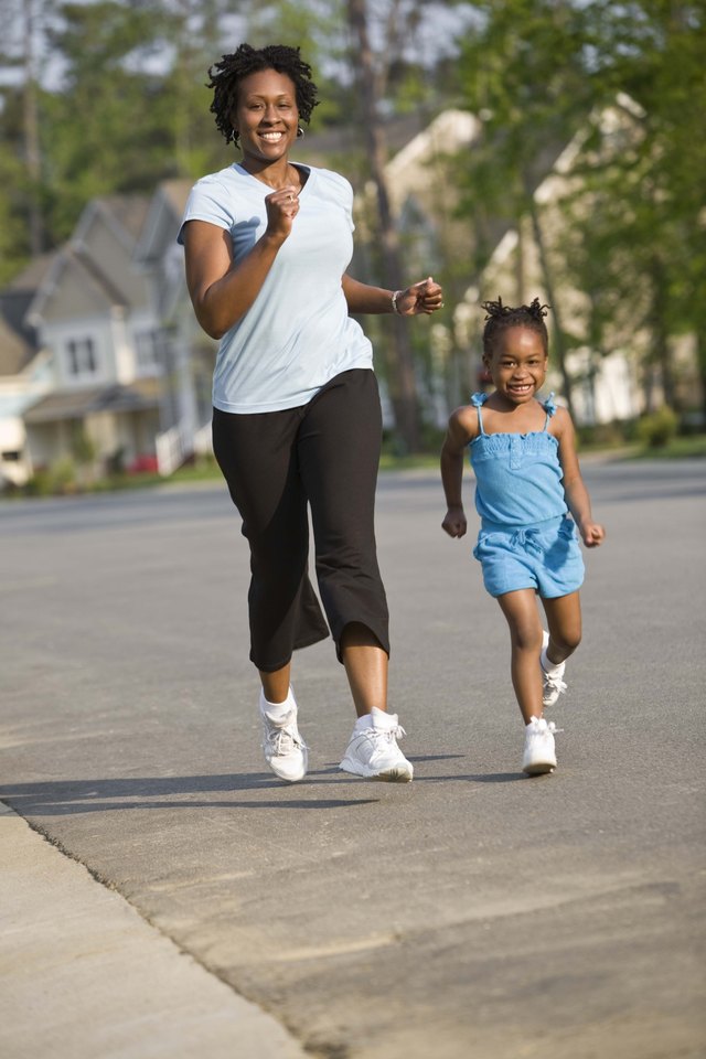 Mother and daughter running on street