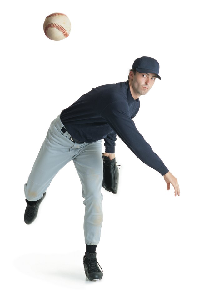 a caucasian man wearing a blue and white baseball uniform is leaning forward after throwing a ball