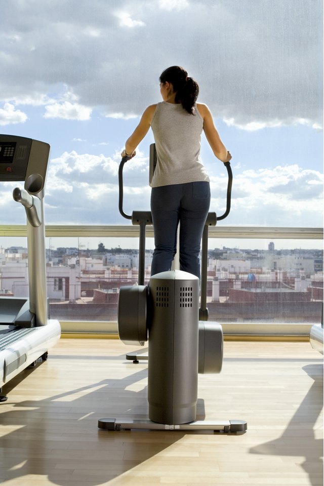 Rear view of a woman on an elliptical machine in front of a window