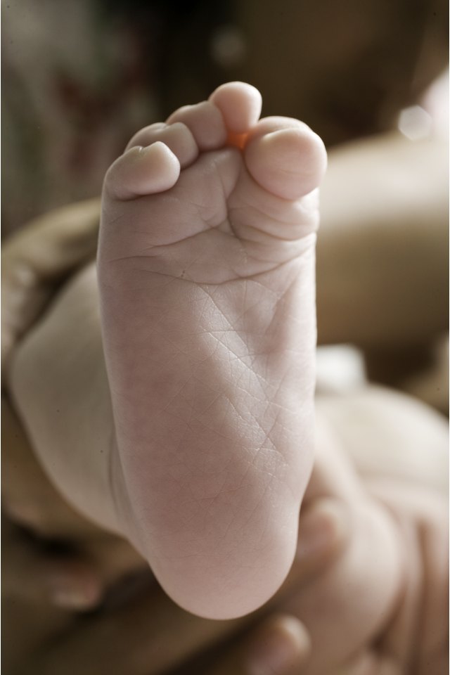 Mother holding baby's (3-6 months) leg, close-up of foot, low section
