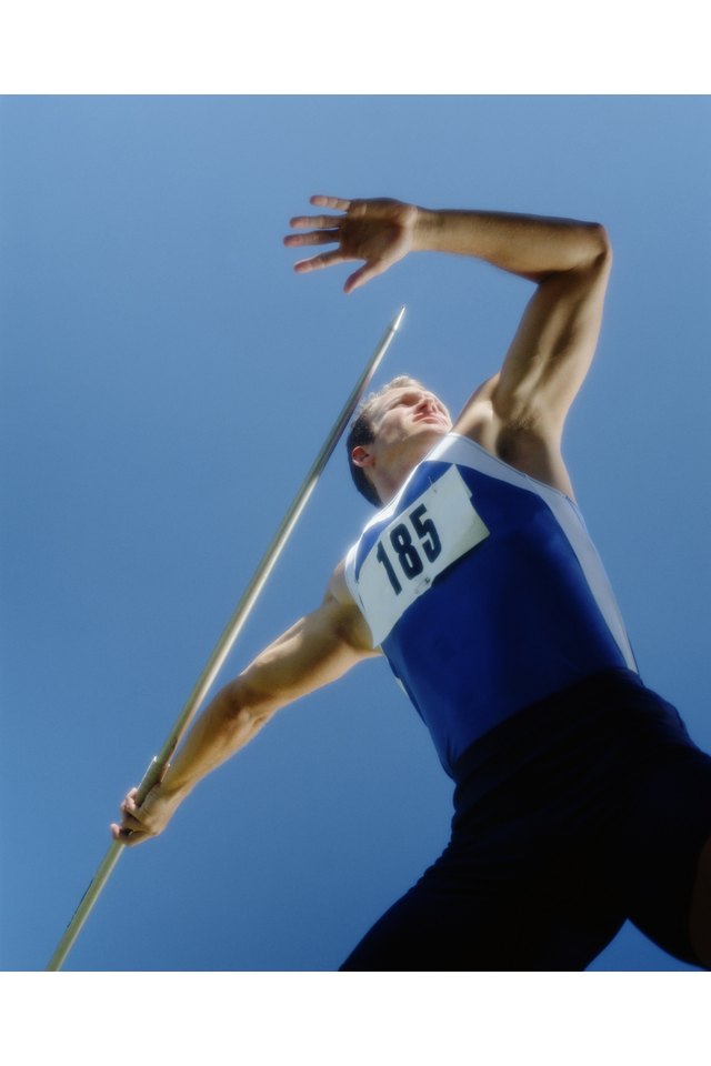 Man with arm extended about to release javelin, low angle