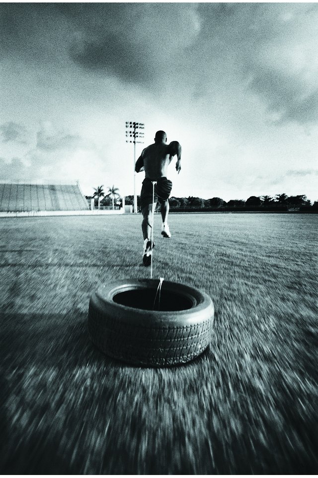 Athlete running with tire tied to rope around waist