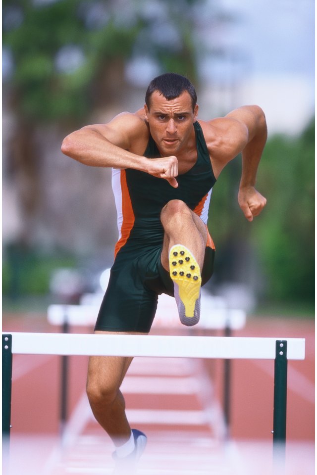 portrait of a young male athlete jumping hurdles