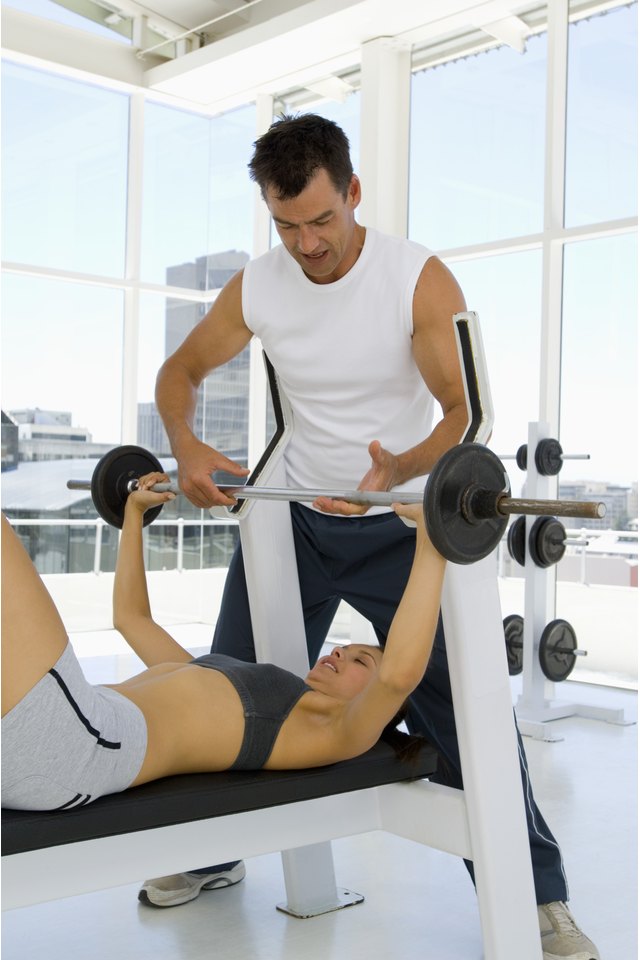 Man helping woman with weightlifting