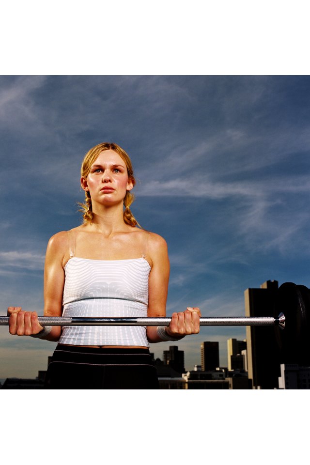 Portrait of a young woman carrying a barbell