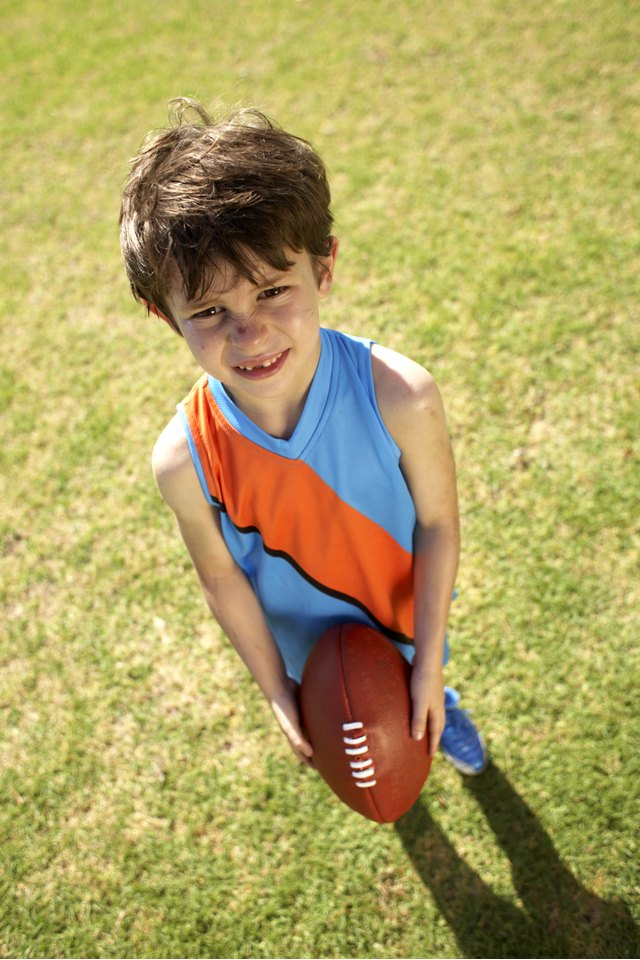Young player holding football, looking up at coach