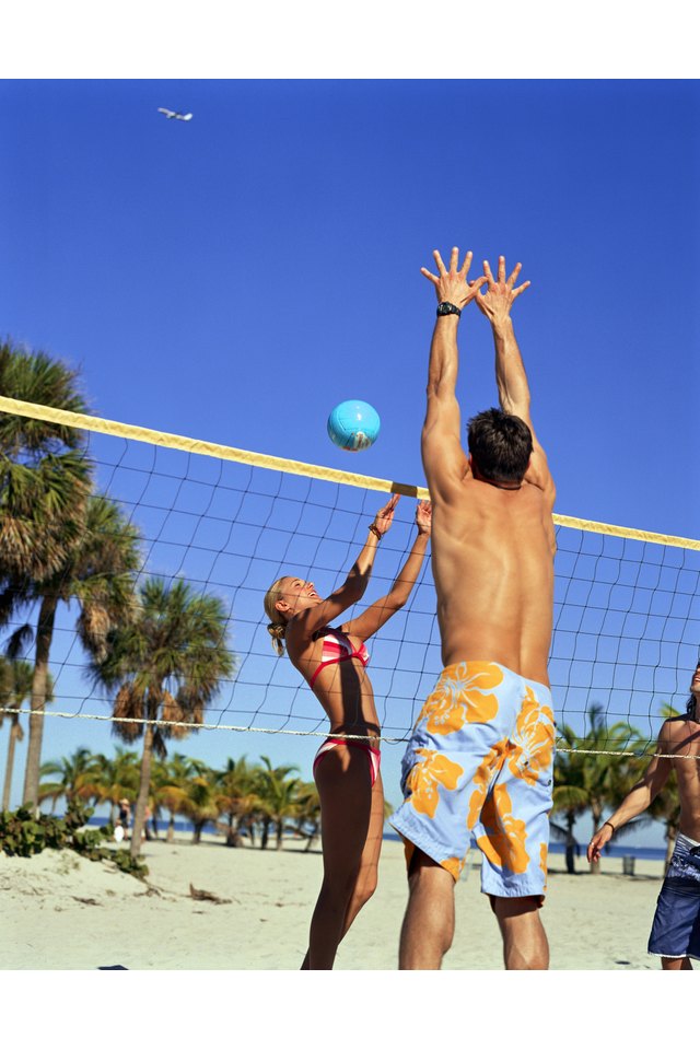 Three people playing volleyball on beach