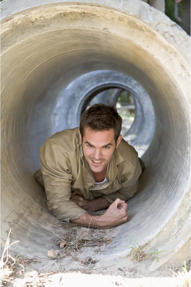 Man crawling through tunnel in obstacle course