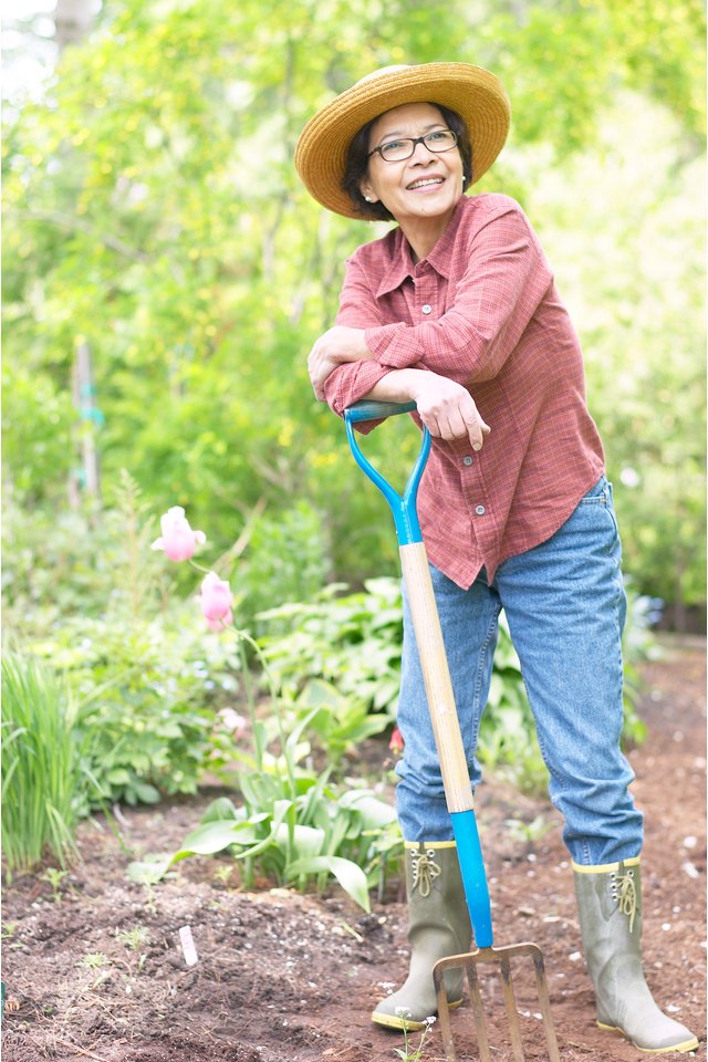 Smiling woman in garden with pitchfork