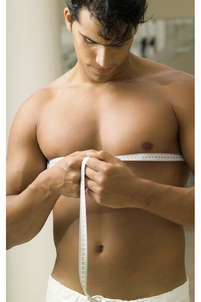 Young man measuring his chest with a measuring tape