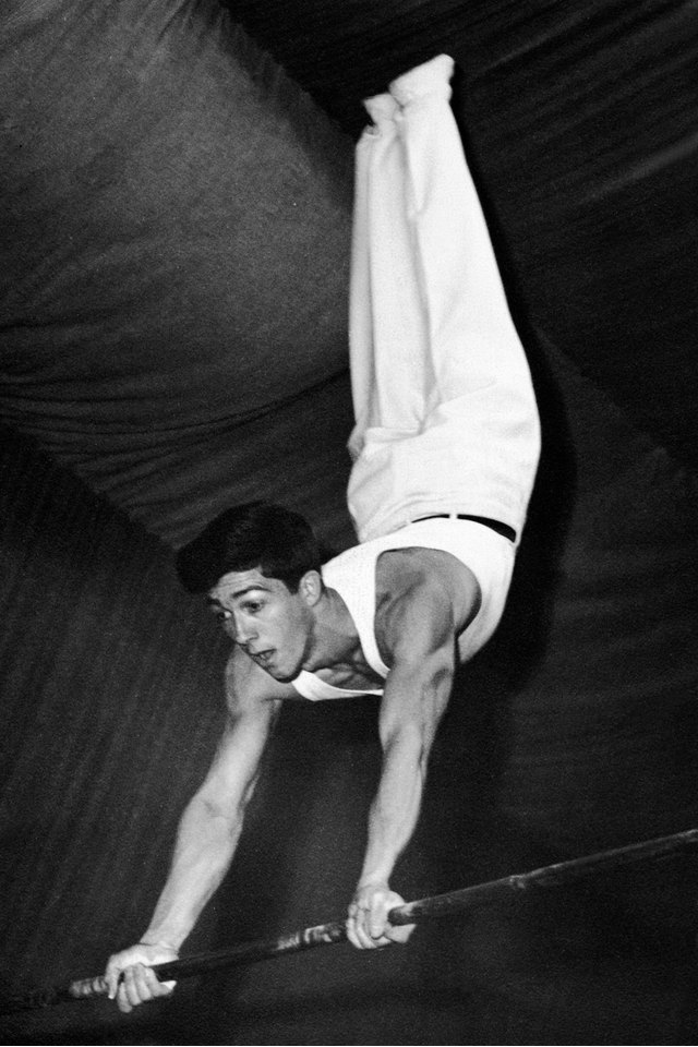 Vintage image of male gymnast swinging on bar