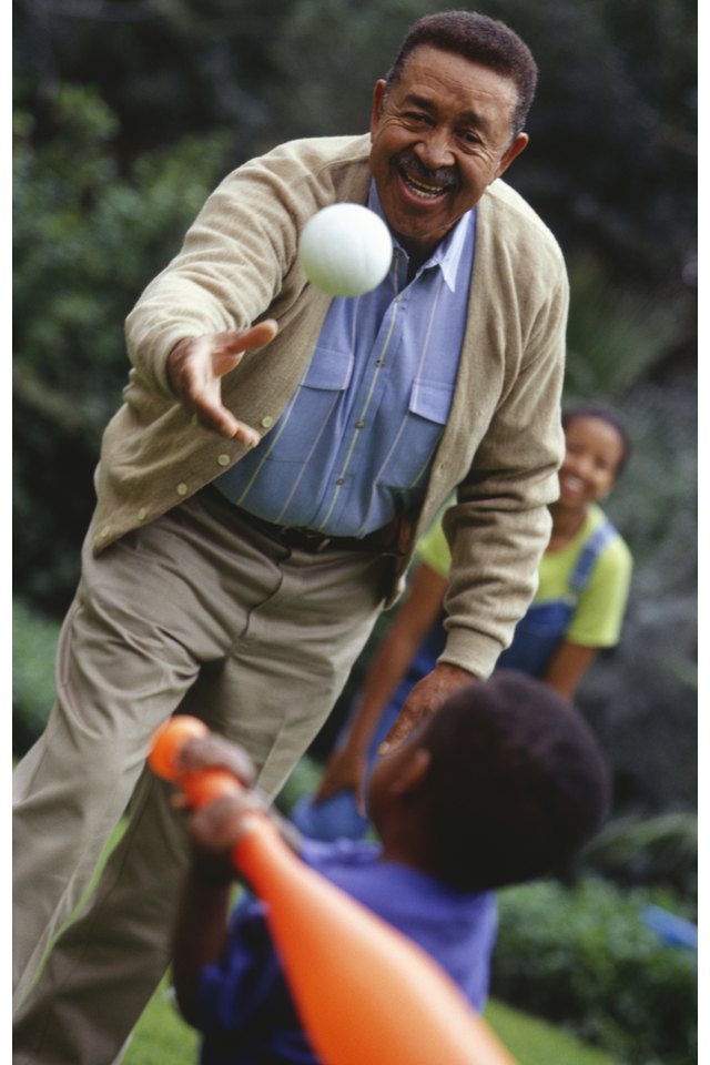 Grandfather and grandchildren playing baseball in garden