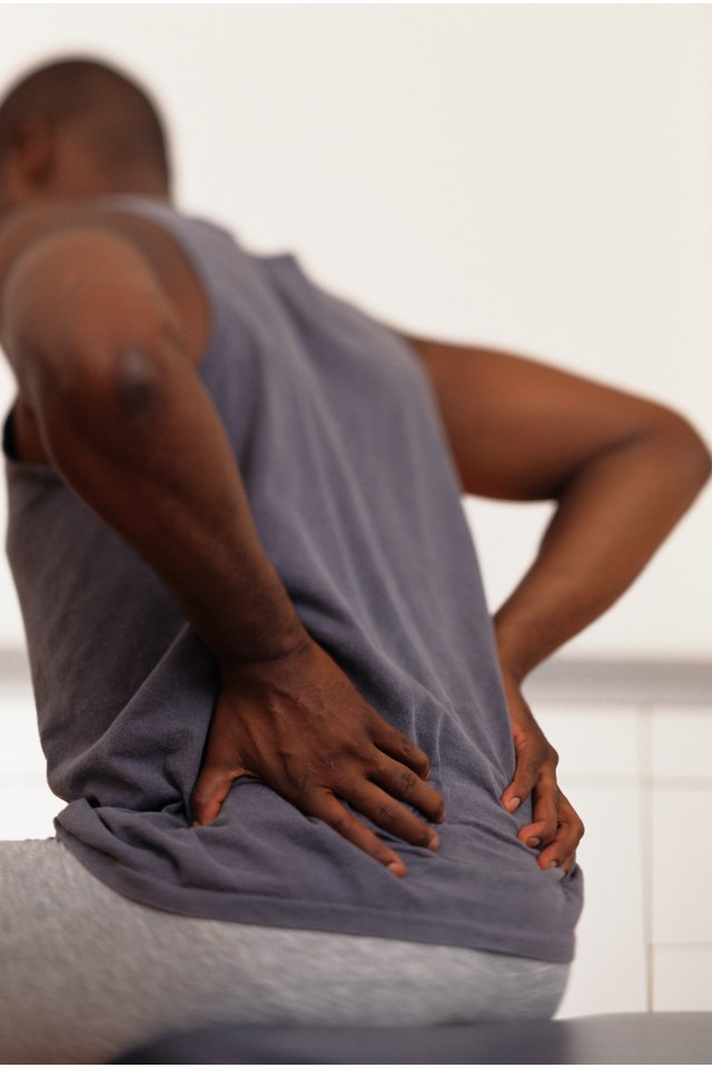 Man sitting on bed in physical therapy centre, surface view