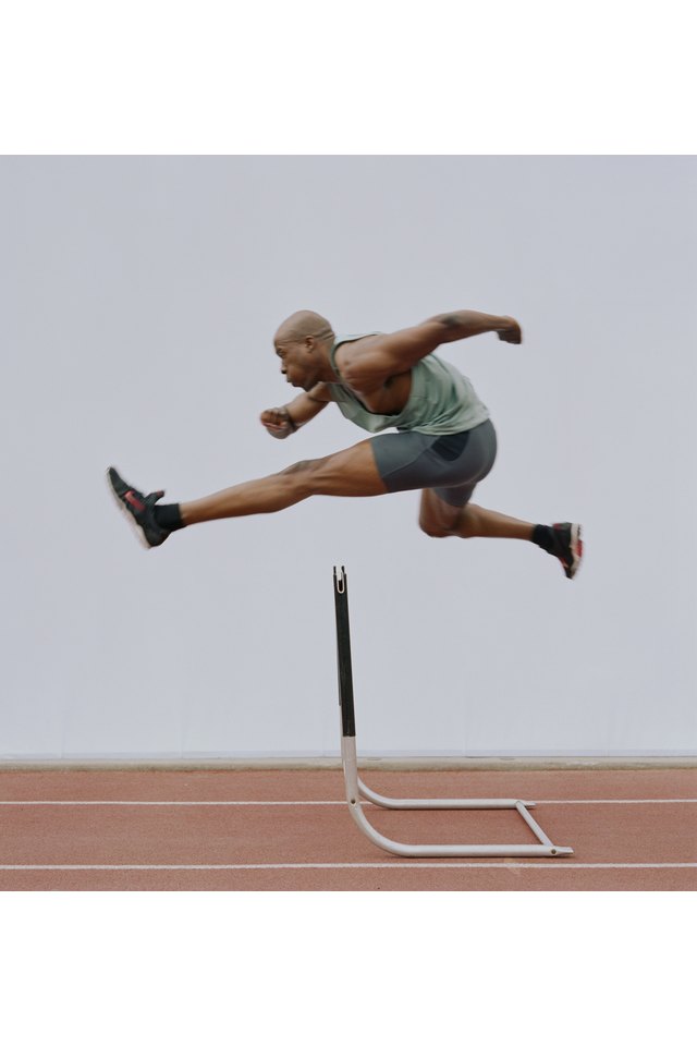 Man jumping hurdle, side view