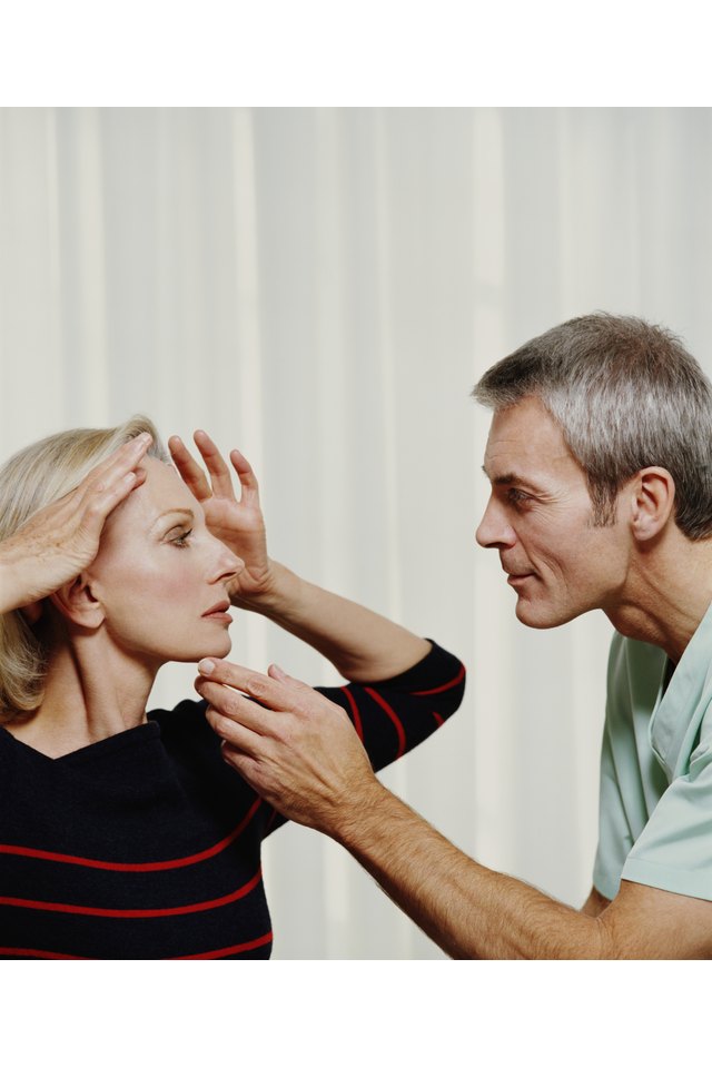 Cosmetic surgeon examing mature woman's face, profile
