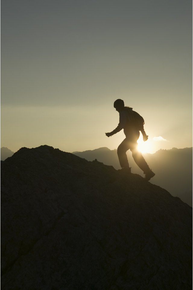 Silhouette of person hiking up mountainside