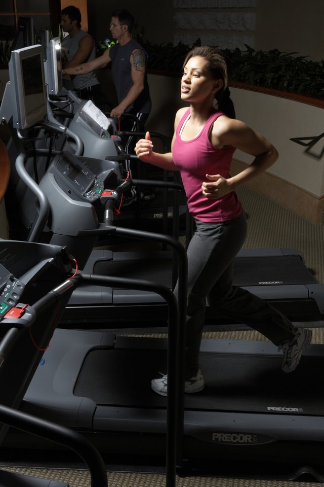 Men and woman exercising on treadmill in gym, side view