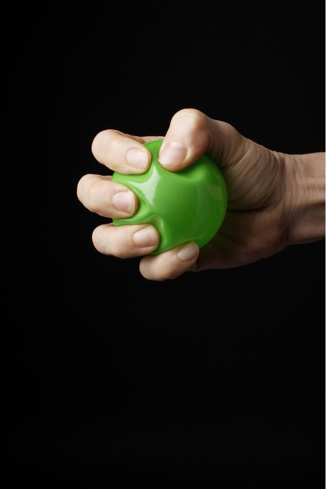Hand gripping green rubber ball