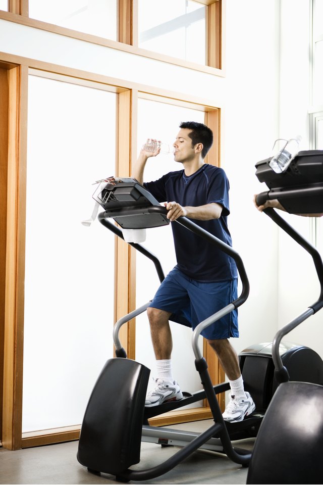 Young man drinking water while working out in gym