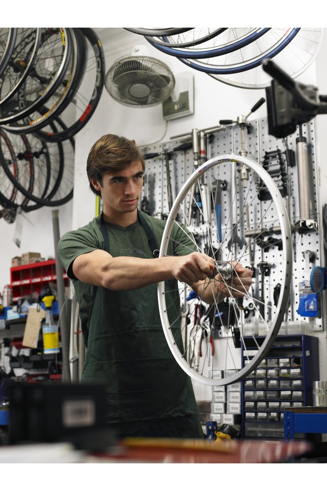 Young man holding wheel of bicycle in shop