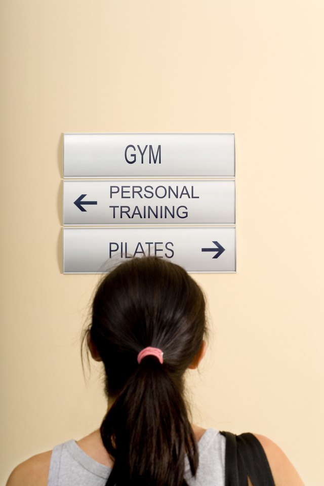 Rear view of a woman reading directional signs in a gym
