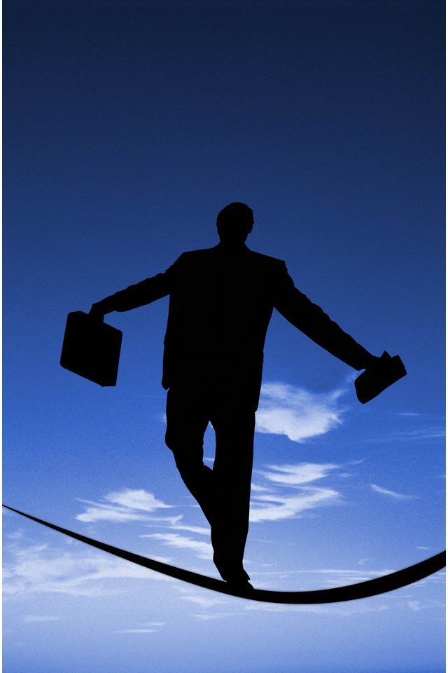 Businessman holding suitcase walking on tightrope, rear view