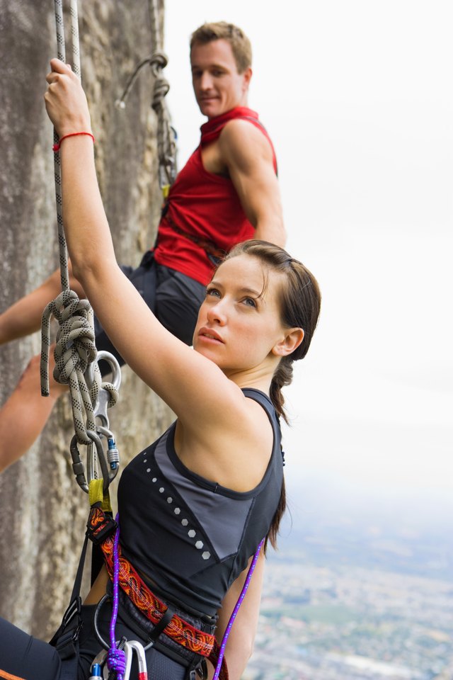 Couple rock climbing on steep cliff