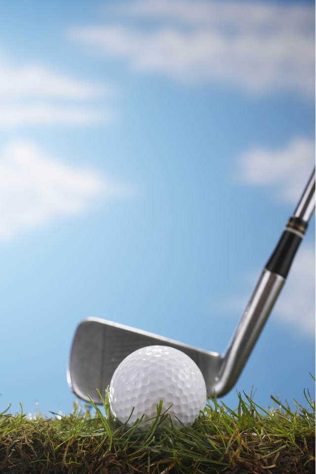 Golf club against golf ball, ground view, close up