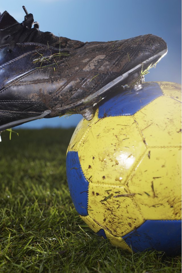 Soccer player resting foot on ball, close-up of foot