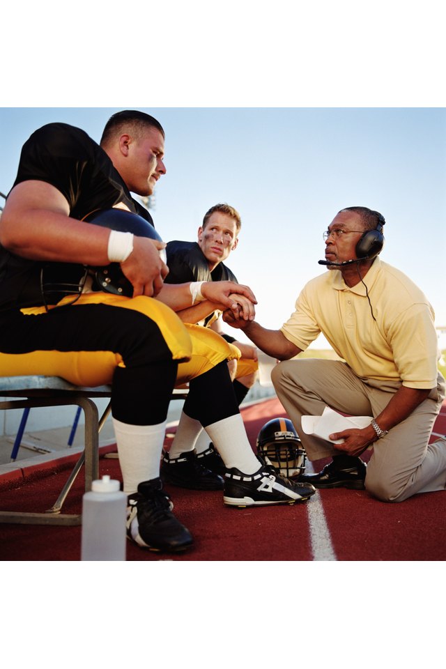 Football players with coach, holding hands together